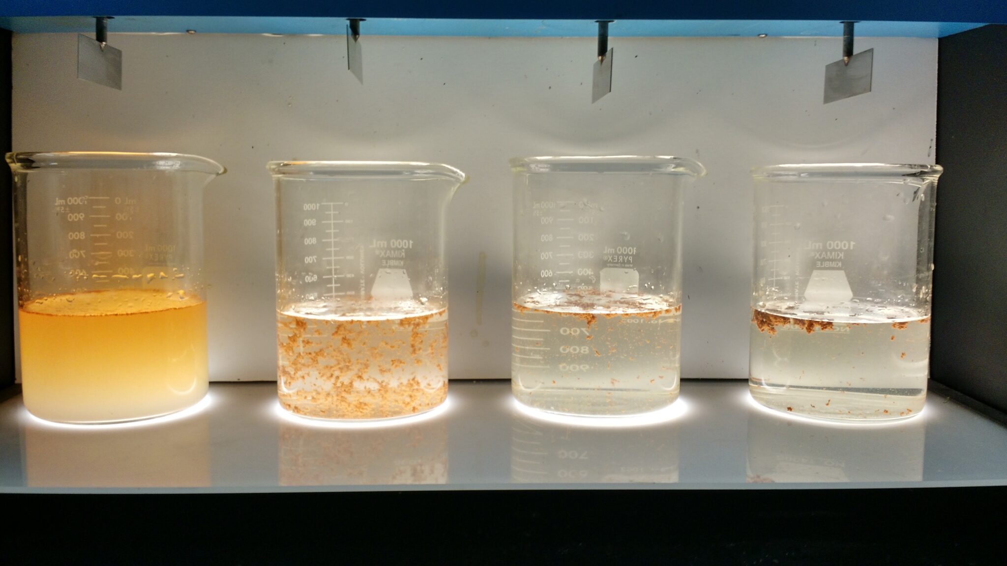 Laboratory beakers showing water treatment chemical progression